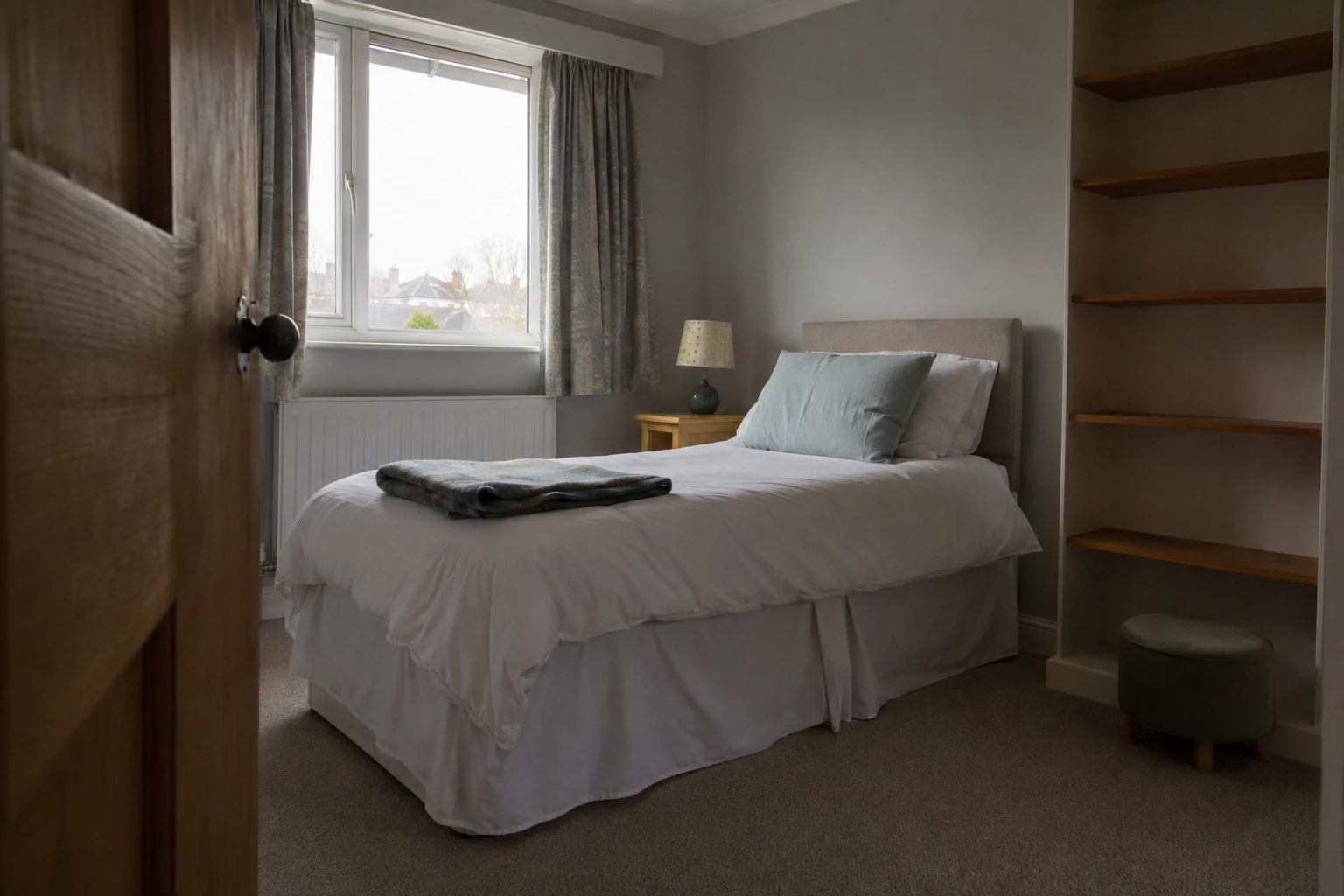 A prepared bedroom with a single bed beside a window